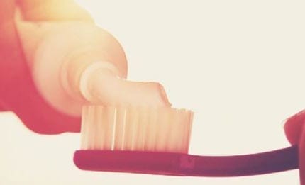 Toothpaste being applied to toothbrush